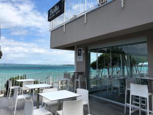 un restaurante con mesas y sillas blancas y el océano en Hotel Ca' Serena, en Sirmione