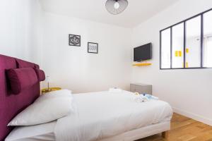 a white bedroom with a bed and a tv at CMG Saint-Antoine Bastille 6 in Paris