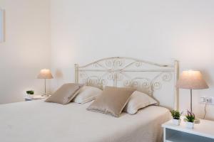 una camera da letto con un letto bianco con cuscini e 2 lampade di Casa Camilla a Siracusa