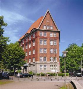 ein großes rotes Backsteingebäude mit spitzem Dach in der Unterkunft Hotel Preuss im Dammtorpalais in Hamburg