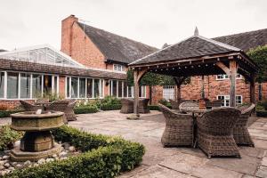 a patio with wicker chairs and a fountain in front of a building at Manor House, Alsager in Alsager