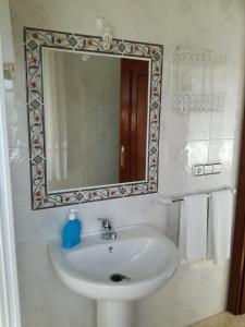 a bathroom with a sink and a mirror and towels at O Cunchal Rooms in Dena