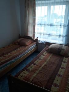 two twin beds in a room with a window at Uniejów Pensjonat Pod Miłorzębem in Uniejow +4 photos
