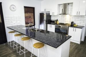 a kitchen with a black counter top and stools at 2 Minutes By Bike - Bright, VIC in Bright