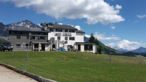 une grande maison sur une colline avec un champ verdoyant dans l'établissement Rifugio "Mai Tardi", à Madesimo