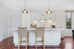 a white kitchen with white cabinets and bar stools at Bright Bliss - Luxury Guesthouse in Bright