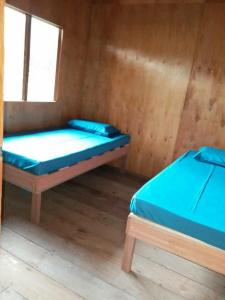 two beds in a wooden room with a window at Long Titi Homestay in Sematan