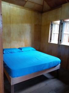 a bed with blue sheets in a room with a window at Long Titi Homestay in Sematan