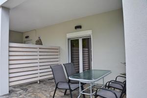 a patio with a glass table and chairs at Mokos Rooms in Perdika