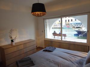 a bedroom with a large window with a boat in the water at Villa d'architecte vue port à 2 pas de la plage in Le Grau-du-Roi