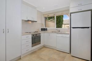 a white kitchen with white appliances and a window at Woody's - In central Bright in Bright