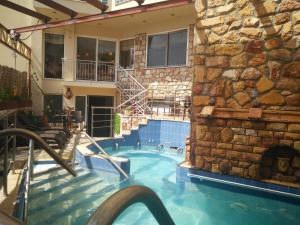 a swimming pool with a stone wall next to a house at 9 Queens Spa Hotel in Loutra Edipsou