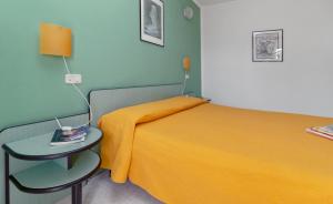 1 dormitorio con cama amarilla y mesa auxiliar en Mini Hotel, en Orbetello
