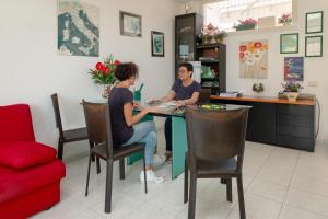 duas pessoas sentadas numa mesa numa cozinha em Mini Hotel em Orbetello