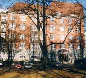 un gran edificio de ladrillo con coches estacionados frente a él en Hotel Preuss im Dammtorpalais, en Hamburgo