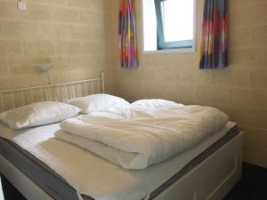 uma cama com lençóis brancos e almofadas em Huisje in Stavelot em Stavelot