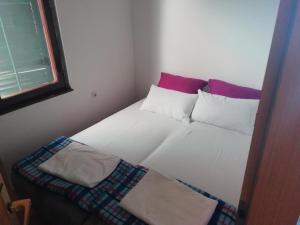 a bedroom with a bed with pillows and a window at apartman holiday budva in Budva