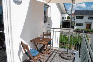 a small balcony with a wooden table and two chairs at Ferienwohnung Elena in Tettnang