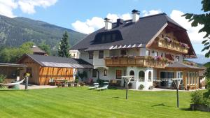 a large house with a porch and a yard at Ferienwohnungen Haus-Holzer in Mauterndorf