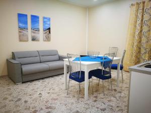un soggiorno con tavolo, sedie e divano di Si Viaggiare Apartments a Partinico