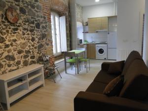 a living room with a couch and a stone wall at Apartamentos Playas de Noja in Noja