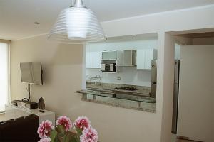 cocina con nevera y barra con flores rosas en MIRAFLORES LUXURY PLACE POOL GYM 2BD, en Lima