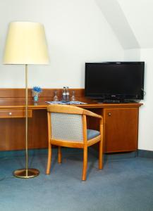 um quarto com uma secretária, uma televisão e uma cadeira em Hotel Zeller Zehnt em Esslingen