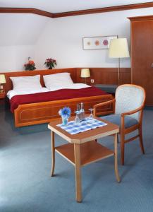 
a room with a bed, table, chair and a lamp at Hotel Zeller Zehnt in Esslingen
