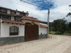 uma casa com uma porta de madeira numa rua em Hospedaje El Mirador em Iza