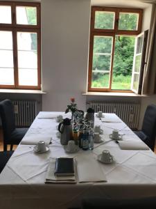 uma mesa com uma toalha de mesa branca e duas janelas em Gästehaus der Abtei Sayn em Bendorf