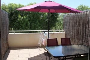 - une table et des chaises sous un parasol sur la terrasse dans l'établissement Appartement la Rochelle, à Aytré