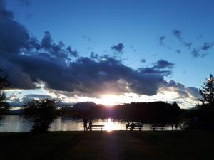 雷丹尼茨恩的住宿－Ferienhof Ressmann-Tratnik，湖上的日落,人们坐在野餐桌上