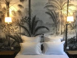 um quarto com uma cama com almofadas brancas e um mural de palma em Apartment Le 1727 em Saint Malo