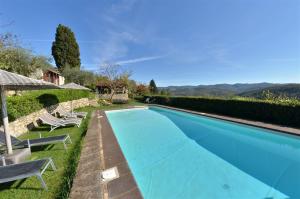 a blue swimming pool with two lawn chairs and an umbrella at Celle di lecchi nel Chianti in San Sano