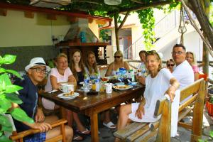 een groep mensen die rond een houten tafel zitten bij Fasoli Studios in Paralia Panteleimonos