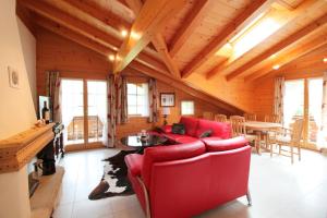 ein Wohnzimmer mit einem roten Sofa und einem Tisch in der Unterkunft Farfalla in Gstaad