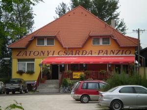 a building with cars parked in front of it at Zátonyi Csárda Panzió in Dunasziget