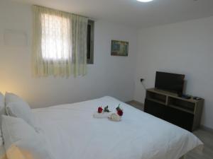 um quarto com uma cama branca e uma televisão em בין יער לים em Shelomi