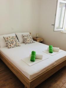a bedroom with a bed with two green towels on it at Apartmani Kronjac in Milna