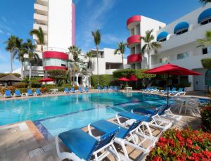 a swimming pool with a patio area with chairs and umbrellas at Mision Mazatlan in Mazatlán