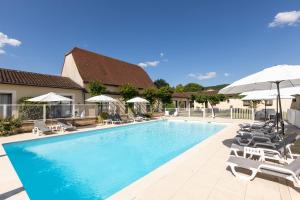- une piscine avec des chaises longues et des parasols dans l'établissement L'Oustal de Vézac, à Vézac