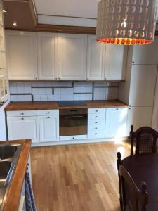 a kitchen with white cabinets and a wooden floor at Kisa Wärdshus & Hotell in Kisa