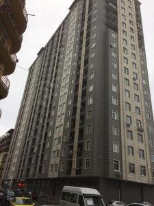 a tall building with cars parked in front of it at Gorgasali street Apartment in Batumi