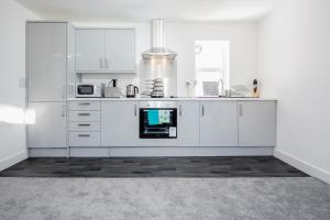 uma cozinha branca com armários e electrodomésticos brancos em Elthorne Luxury Apartments - Uxbridge em Uxbridge