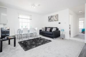 a living room with a black couch and a table at Elthorne Luxury Apartments - Uxbridge in Uxbridge