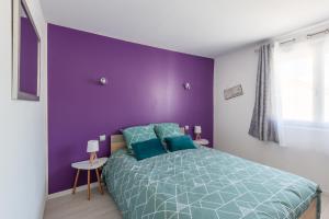 Dormitorio púrpura con cama y pared púrpura en La Maisonnette Narbonnaise (Proche Grands Buffets), en Narbona