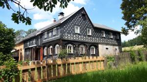 a black house with a wooden fence in front of it at Prázdninový dům Nové Hraběcí in Šluknov