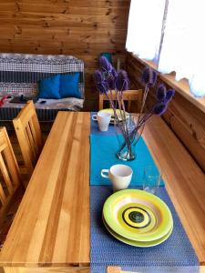 una mesa con un plato amarillo y un jarrón con flores púrpuras en Domki Baltyk, en Dąbki
