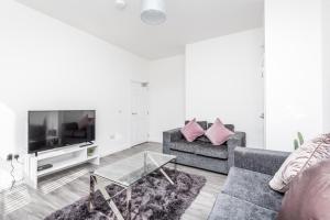 a living room with a couch and a tv at Casa Fresa - Cowgate Apartment in Dundee