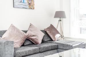 a gray couch with pillows in a living room at Casa Fresa - Cowgate Apartment in Dundee